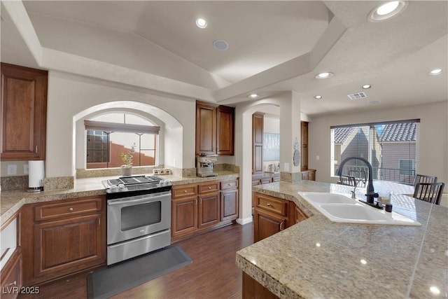 kitchen with lofted ceiling, sink, stainless steel range oven, and dark hardwood / wood-style flooring