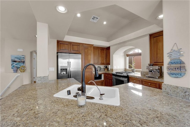 kitchen with kitchen peninsula, vaulted ceiling, appliances with stainless steel finishes, and sink