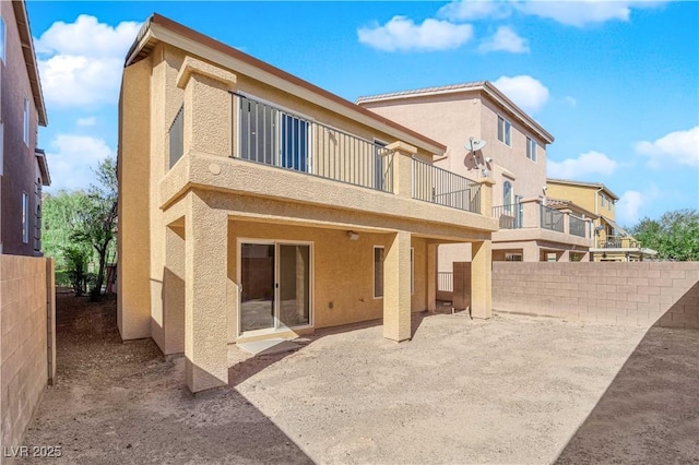 rear view of property featuring a balcony and a patio