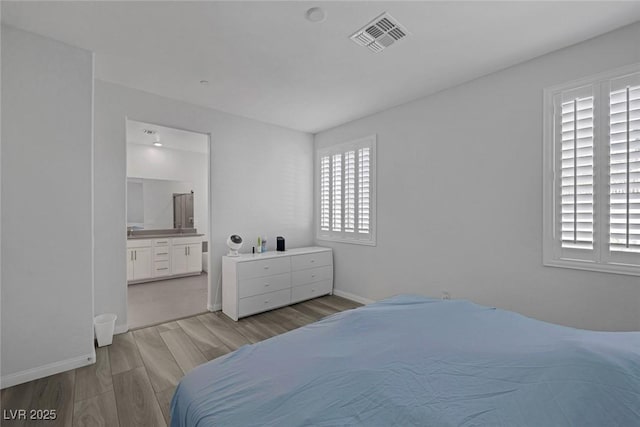 bedroom featuring ensuite bathroom, light hardwood / wood-style floors, and multiple windows