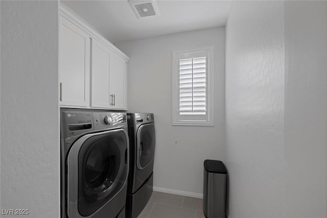 laundry area with light tile patterned floors, separate washer and dryer, and cabinets