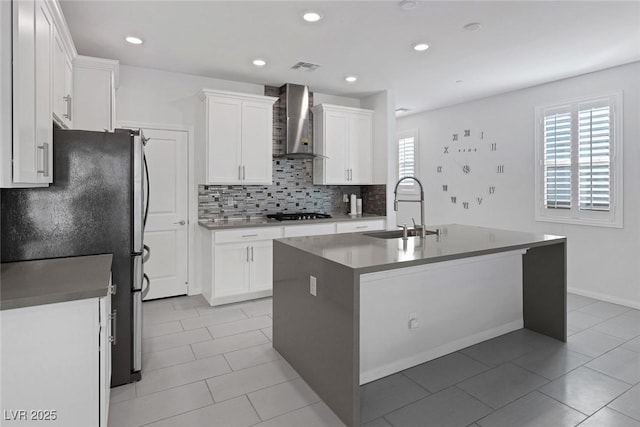 kitchen featuring sink, white cabinets, wall chimney exhaust hood, and stainless steel refrigerator