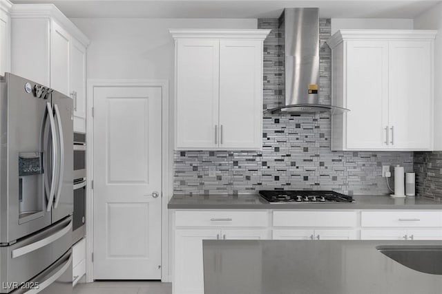 kitchen with white cabinetry, backsplash, stainless steel appliances, and wall chimney exhaust hood