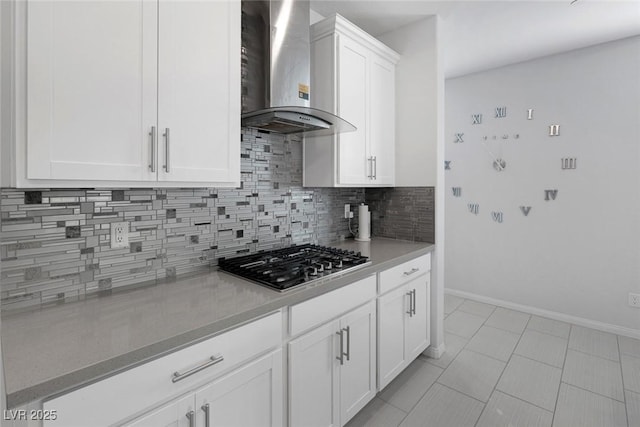 kitchen featuring stainless steel gas stovetop, light tile patterned floors, decorative backsplash, wall chimney exhaust hood, and white cabinets