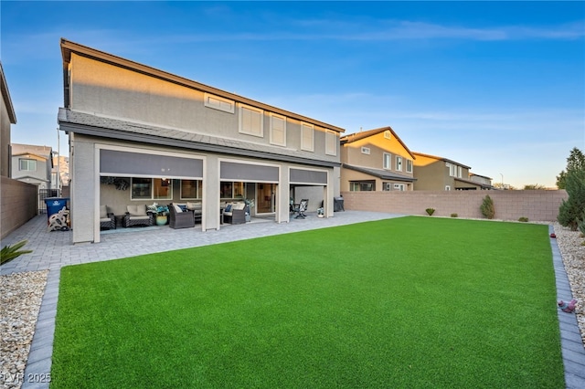 back of house with outdoor lounge area, a lawn, and a patio