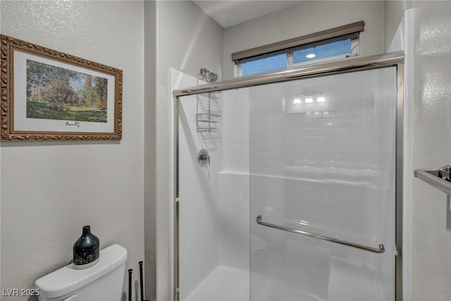 bathroom with toilet and a shower with door