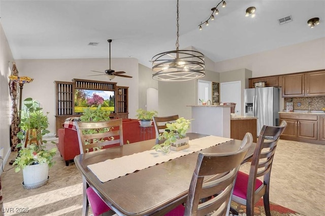 tiled dining area with ceiling fan with notable chandelier and vaulted ceiling