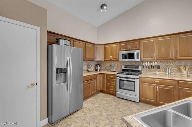 kitchen featuring stainless steel appliances, decorative backsplash, sink, light tile patterned flooring, and high vaulted ceiling