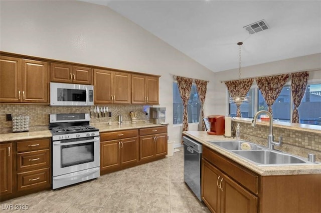 kitchen with stainless steel appliances, backsplash, decorative light fixtures, and sink