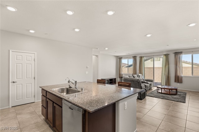 kitchen featuring dishwasher, a center island with sink, sink, dark brown cabinetry, and light stone countertops