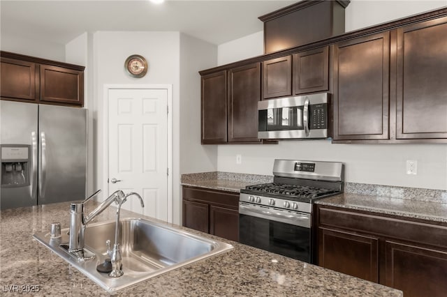 kitchen featuring light stone countertops, sink, dark brown cabinetry, and stainless steel appliances