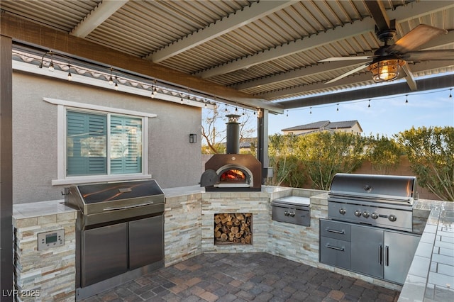 view of patio / terrace featuring grilling area, ceiling fan, area for grilling, and an outdoor stone fireplace