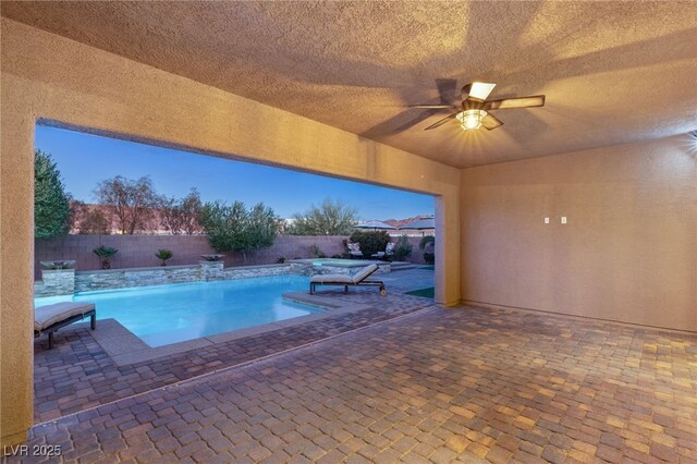 pool at dusk with ceiling fan and a patio