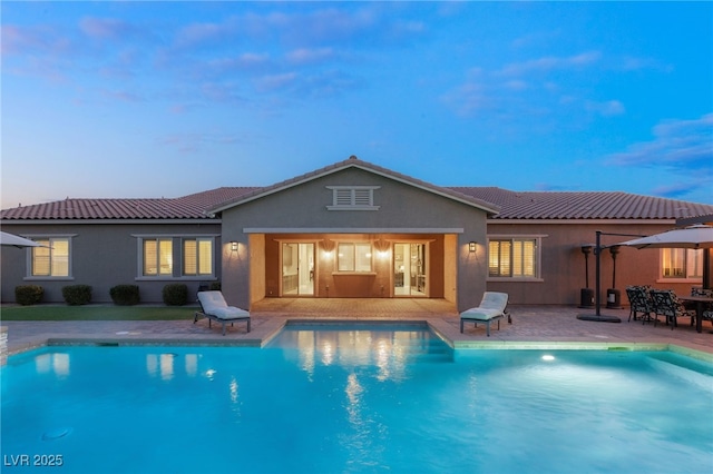 pool at dusk featuring a patio