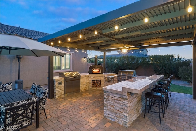 patio terrace at dusk with grilling area and an outdoor kitchen