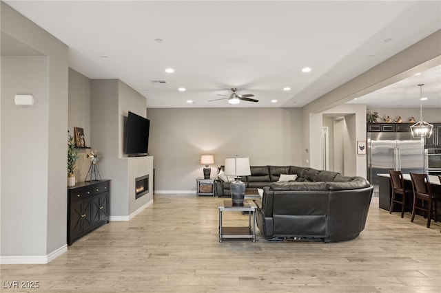 living room with ceiling fan and light hardwood / wood-style flooring