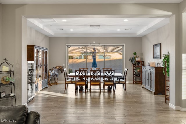 dining space featuring an inviting chandelier and a raised ceiling