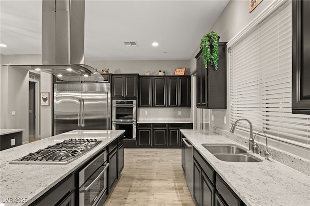 kitchen with light stone countertops, sink, island exhaust hood, and stainless steel appliances