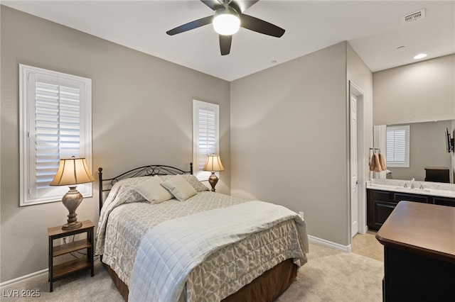 carpeted bedroom featuring ceiling fan, ensuite bathroom, and sink