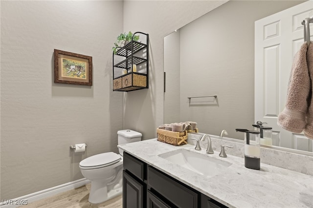 bathroom with toilet, hardwood / wood-style flooring, and vanity