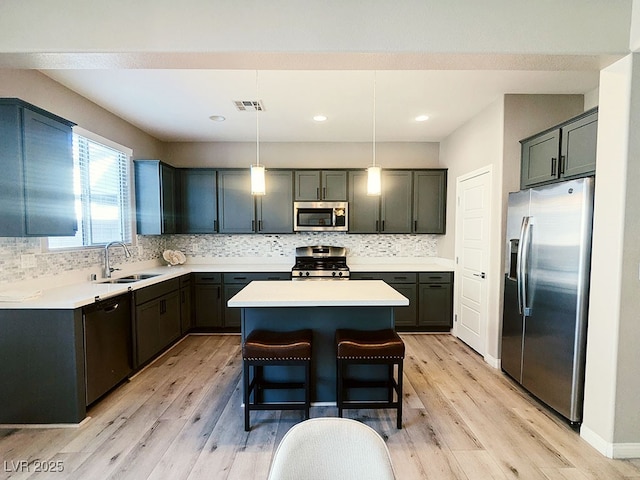 kitchen featuring a kitchen island, pendant lighting, sink, appliances with stainless steel finishes, and a breakfast bar area