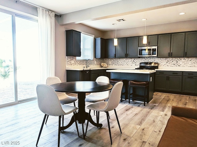 kitchen with plenty of natural light, pendant lighting, appliances with stainless steel finishes, and sink