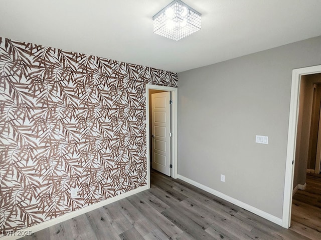 empty room with dark hardwood / wood-style floors and a notable chandelier