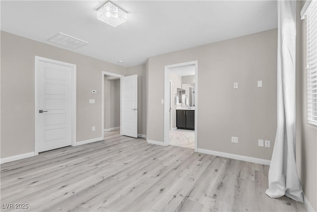 unfurnished bedroom featuring connected bathroom and light wood-type flooring