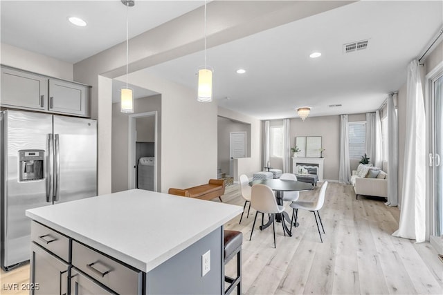 kitchen with a kitchen island, pendant lighting, washer / clothes dryer, gray cabinetry, and stainless steel fridge with ice dispenser