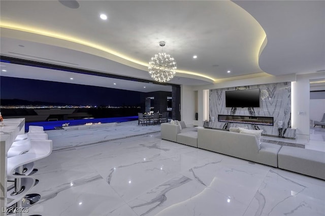 living room featuring a raised ceiling, a chandelier, and a fireplace