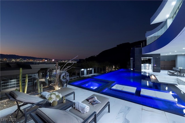 pool at dusk featuring a patio area and an in ground hot tub