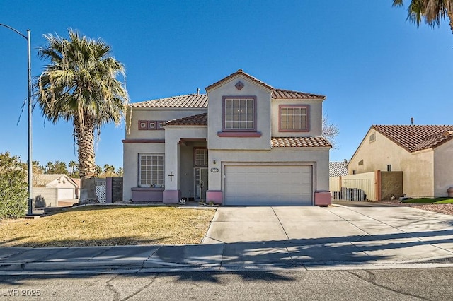 mediterranean / spanish house with stucco siding, concrete driveway, an attached garage, fence, and a tiled roof