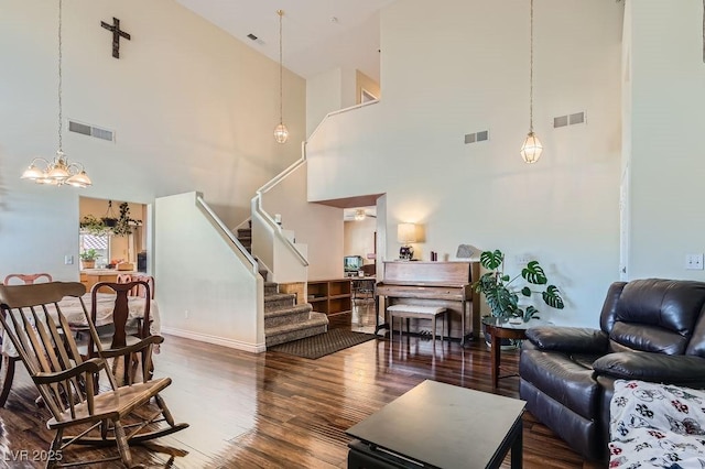 living room with a chandelier, a towering ceiling, and hardwood / wood-style floors