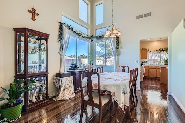 dining room featuring a high ceiling, dark hardwood / wood-style floors, and an inviting chandelier