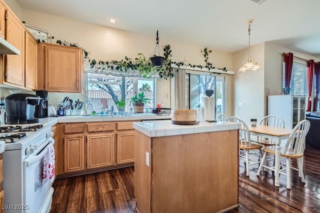 kitchen featuring tile counters, a kitchen island, hanging light fixtures, white gas stove, and dark hardwood / wood-style floors