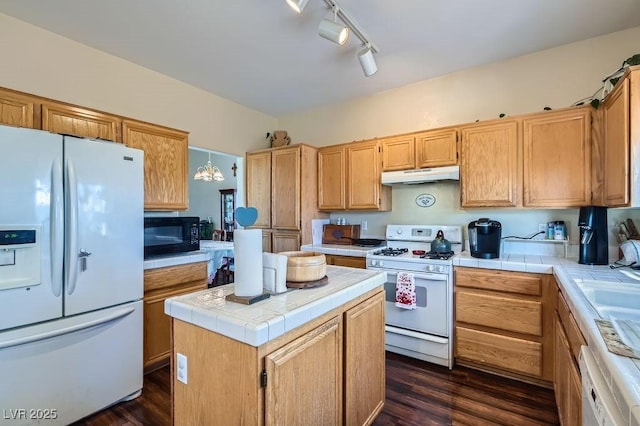 kitchen with white appliances, a center island, dark hardwood / wood-style floors, a chandelier, and tile countertops