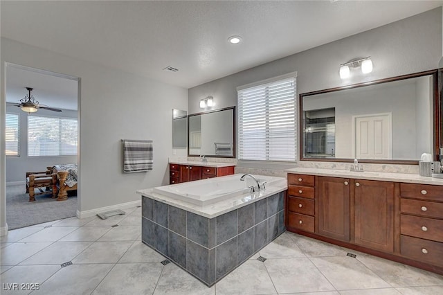 bathroom with tiled bath, ceiling fan, tile patterned flooring, and vanity