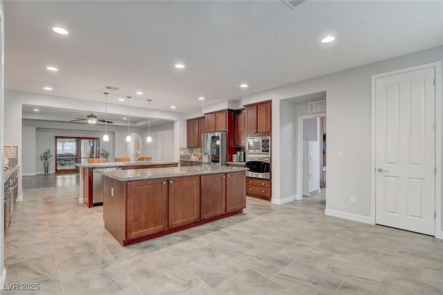 kitchen featuring decorative light fixtures, appliances with stainless steel finishes, a center island, and ceiling fan