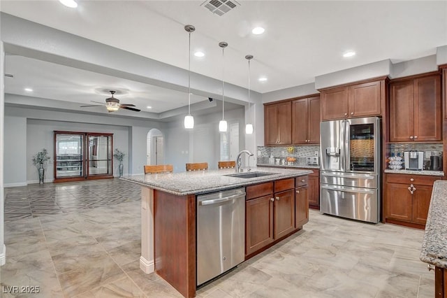 kitchen featuring decorative light fixtures, an island with sink, appliances with stainless steel finishes, and sink