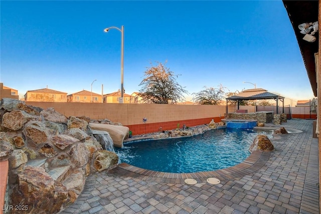 pool at dusk featuring a gazebo and pool water feature