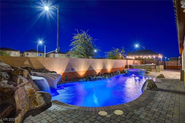 pool at twilight with an in ground hot tub, a patio area, a gazebo, and pool water feature