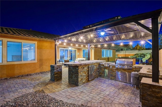 patio at night with exterior kitchen and grilling area