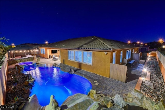 pool at night with a gazebo, a patio, and an in ground hot tub