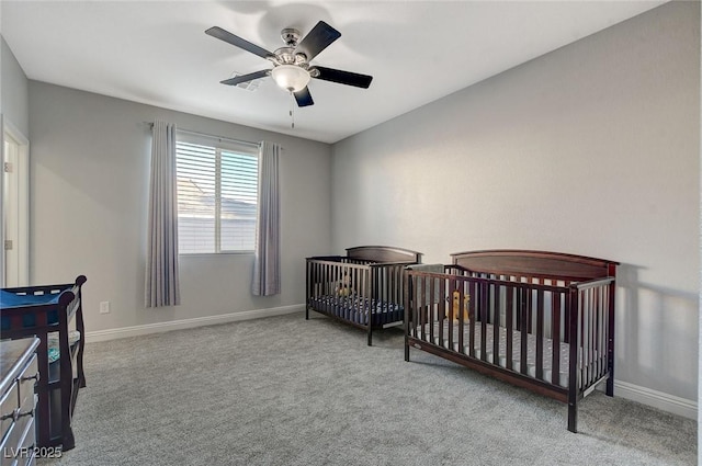 bedroom with ceiling fan, light colored carpet, and a crib