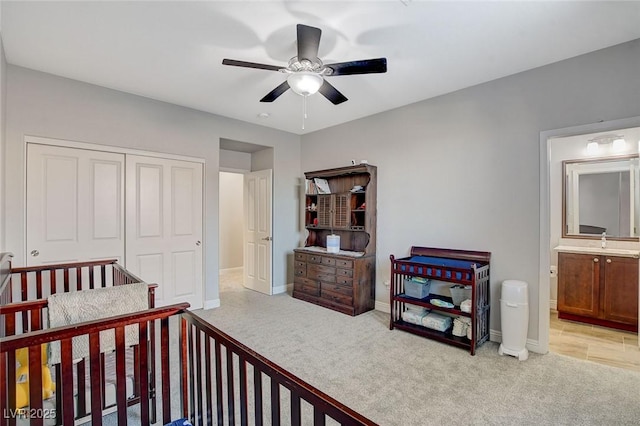 carpeted bedroom featuring ceiling fan, ensuite bathroom, a closet, and sink