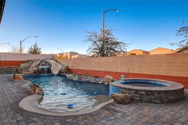 view of swimming pool with pool water feature, a patio area, a water slide, and an in ground hot tub