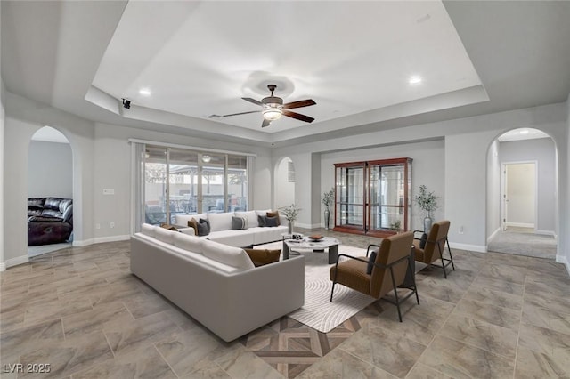 living room featuring ceiling fan and a raised ceiling