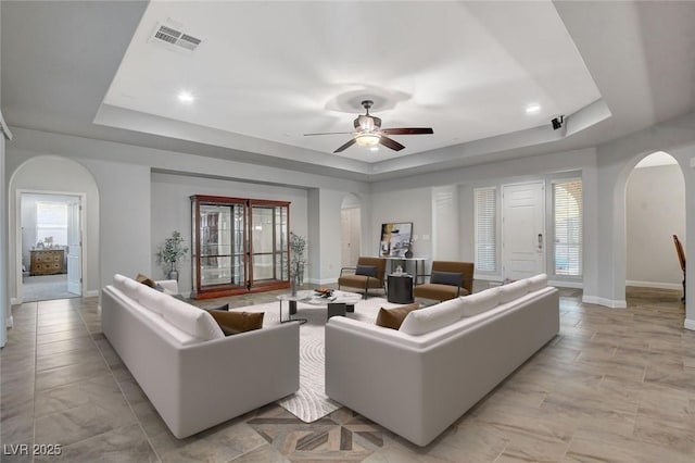 living room featuring ceiling fan and a tray ceiling