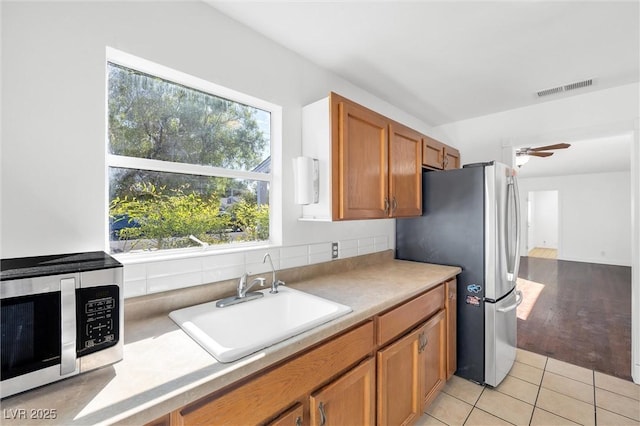 kitchen with light tile patterned floors, stainless steel appliances, ceiling fan, and sink