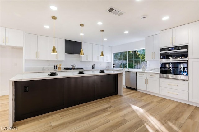 kitchen with a center island, hanging light fixtures, light stone countertops, stainless steel appliances, and white cabinets